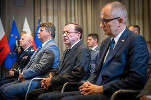 Uroczystość wręczenia medali - Minister Spraw Wewnętrznych i Administracji Mariusz Kamiński siedzący obok innych osób.