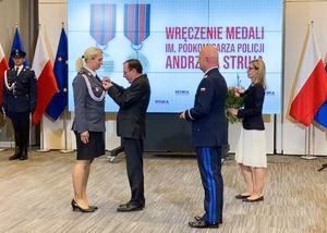 Minister Spraw Wewnętrznych i Administracji Mariusz Kamiński przypina medal policjantce.