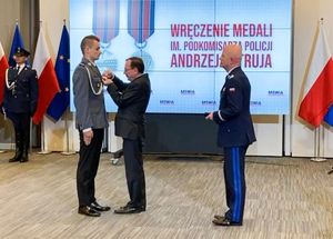 Minister Spraw Wewnętrznych i Administracji Mariusz Kamiński przypina medal policjantowi.