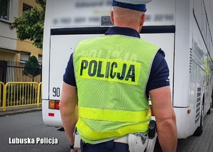 Policjant drogówki stojący przed autokarem.