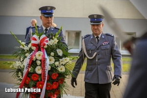 Policjanci składają kwiaty pod pamiątkowym obeliskiem