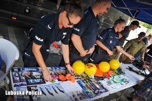 Policjanci rozdają ulotki i policyjne gadżety