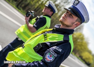 Policjanci drogówki stojący przy drodze.