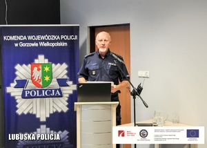 Policjant przemawiający na mównicy.