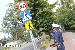 policjant kontroluje znak oznakowanie na drodze