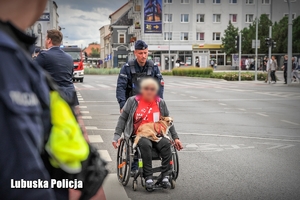 policjant przeprowadza kobietę na wózku