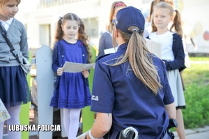 Policjantka wręcza plan lekcji uczniom.