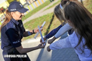 policjantka zakłada odblaski dzieciom na ręce