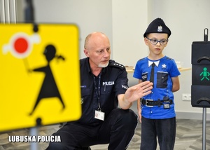 policjant z chłopcem w miasteczku ruchu drogowego