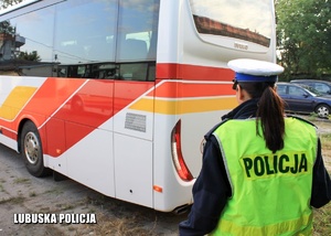 Policjantka stoi za autobusem.