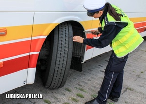 Policjantka sprawdza ogumienie autobusu.