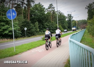 Policjanci jadący rowerem po drodze rowerowej.