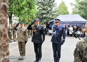 Funkcjonariusze służb mundurowych oddają honor przed pomnikiem.