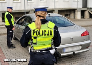 Policjanci drogówki przy kontrolowanym pojeździe.