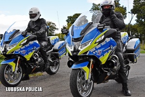 Policjanci stojący na policyjnym motocyklu.