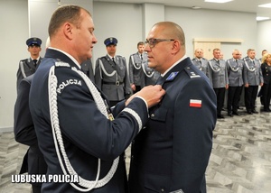 Komendant Wojewódzki Policji w Gorzowie Wielkopolskim przypina medal policjantowi.