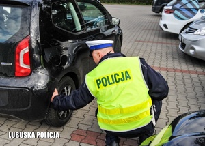 Policjant drogówki sprawdza stan techniczny kontrolowanego pojazdu.