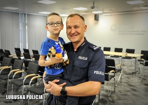 Policjant trzymający chłopca pozują do zdjęcia.