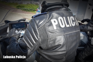 Plecy policyjnego motocyklisty z napisem policja na kombinezonie