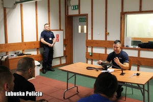 policjant tłumaczy mężczyznom obsługę broni