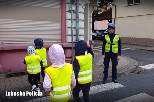 Policjantka pomaga przejść dzieciom przez przejście