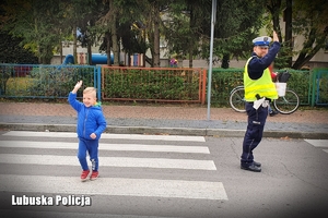 Policjant pomaga chłopcu przejść przez jezdnię