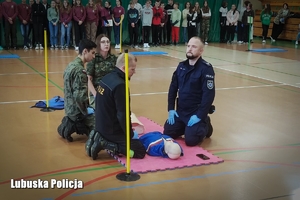 Żołnierze i policjant uczą młodzież jak przeprowadzać resuscytacje