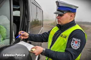 policjant daje kierowcy dokumenty do podpisania