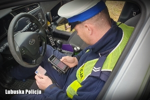 Policjant sprawdza dane kierującego w radiowozie