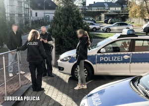 Niemieccy policjanci stojący przy radiowozie.