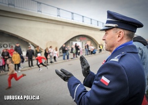 Policjant oklaskuje uczestników biegu niepodległościowego.