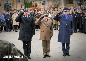 Funkcjonariusze służb mundurowych oddają honor przed pomnikiem na uroczystościach niepodległościowych.