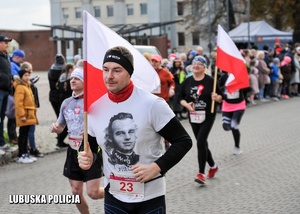 Uczestnik biegu z flagą Polski podczas biegu.