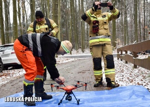 Operator drona wspólnie ze strażakami przygotowuje drona do lotu podczas ćwiczeń sztabowych.
