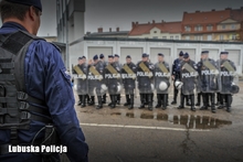Policjant na tle stojących w rzędzie policjantów.