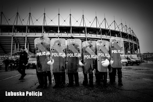 Policjanci oddziałów prewencji podczas ćwiczeń stojący na tle stadionu - zdjęcie czarno-białe.