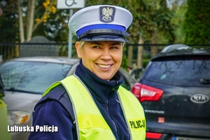 Uśmiechnięta policjantka kieruje ruchem przy cmentarzu