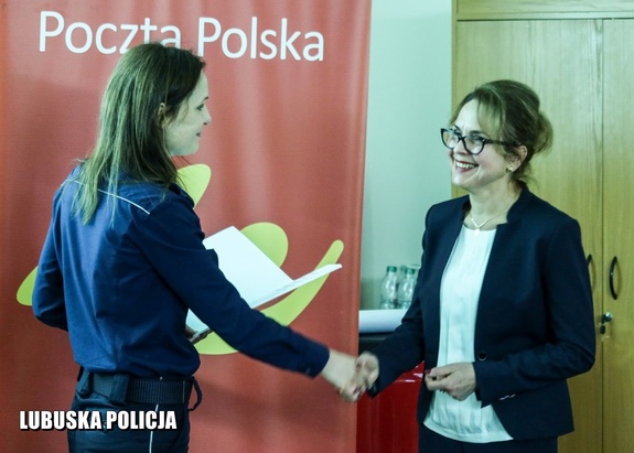 Policjantka wręcza podziękowanie pracownicy Poczty Polskiej.