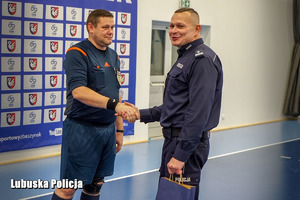 policjant wręcza nagrodę sędziemu piłkarskiemu
