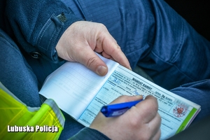Policjant wypisuje blankiet mandatu karnego