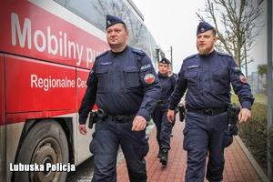 policjanci idą obok krwiobusa