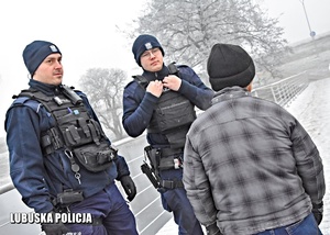 Policjanci w zimowy dzień podczas patrolu rozmawiają z mężczyzną.