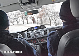 Policjanci jadący radiowozem.