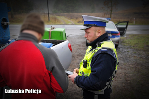Policjant drogówki rozmawia z kierowcą przy pojeździe
