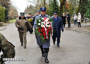 Delegacja służb mundurowych składa kwiaty przed pomnikiem.