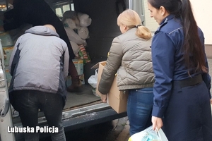 policjantka, kobieta i mężczyzna pakują zebrane produkty do busa
