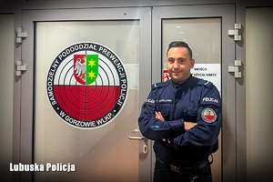 Policjant na tle logo Samodzielnego Pododdziału Prewencji Policji w Gorzowie Wielkopolskim