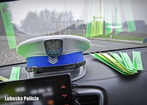 Czapka policjant drogówki i odblaskowe opaski na desce rozdzielczej radiowozu