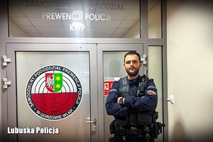 Policjant przy drzwiach z logo Samodzielnego Pododdziału Prewencji Policji w Gorzowie Wielkopolskim