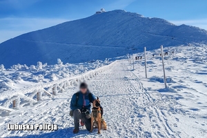 mężczyzna z policyjnym psem stoją przed szczytem góry